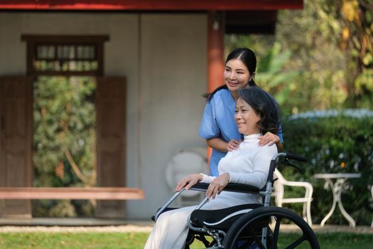 Elderly asian senior woman on wheelchair with nurse. Nursing home hospital garden concept