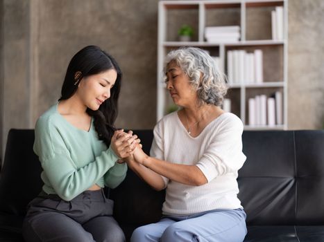 Daughter talking to sad mother holding hand comforting upset having problem.