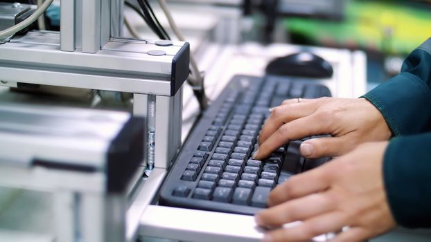 A close-up, hands work on the keyboard. a worker at an enterprise, a production, in a workshop, regulates the operation of a mechanized process through a computer. High quality photo