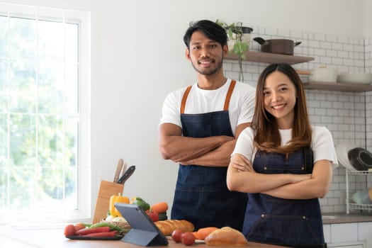 Romantic couple is cooking on kitchen. Handsome man and attractive young woman are having fun together while making salad. Healthy lifestyle concept...