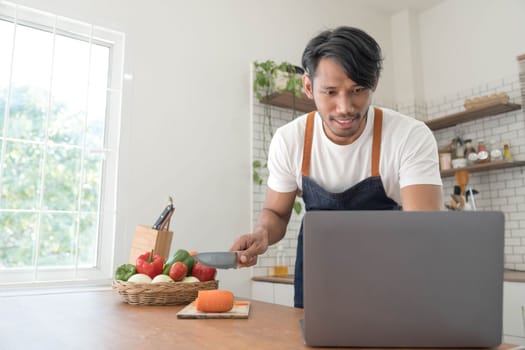 An Asian young man cooking , preparing breakfast with healthy food in kitchen at home , healthy lifestyle..