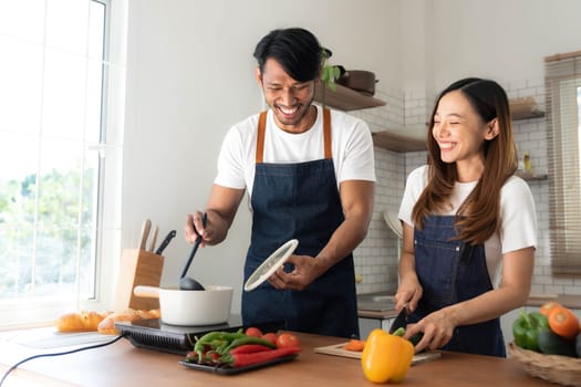 Romantic couple is cooking on kitchen. Handsome man and attractive young woman are having fun together while making salad. Healthy lifestyle concept...