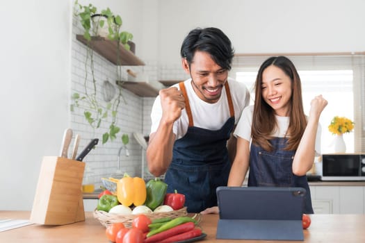 Romantic couple is cooking on kitchen. Handsome man and attractive young woman are having fun together while making salad. Healthy lifestyle concept...