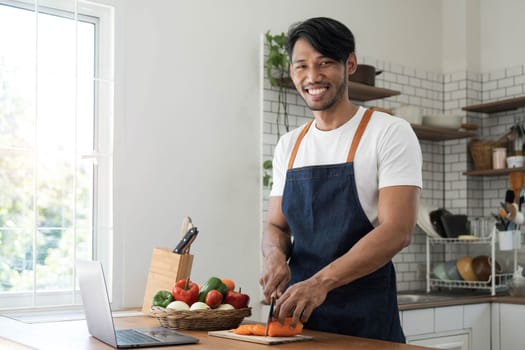 An Asian young man cooking , preparing breakfast with healthy food in kitchen at home , healthy lifestyle..