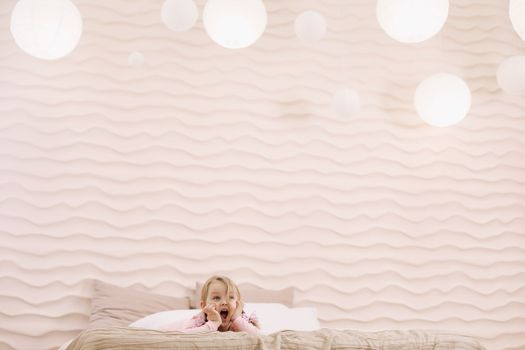 Morning of little girl in a comfortable bedroom. Happy child girl having fun and plays in bed.