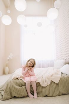 Morning of little girl in a comfortable bedroom. Happy child girl having fun and plays in bed.
