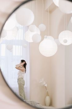 Portrait of calm pretty girl. Portrait of the woman reflected in mirror in a cozy light room in the morning