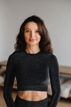 Portrait of a beautiful woman in black sportswear indoors.