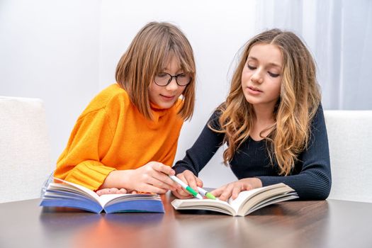 two young girls, sisters, are preparing homework with books. children of generation z. High quality photo