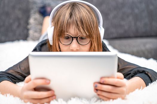 teenager with headphones and tablet on couch. children and modern technology, generation z. High quality photo