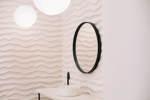 Modern interior with stylish round mirror by beige wall in a cozy room, copy space, elegant accessories in stylish home decor.
