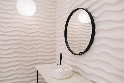 Modern interior with stylish round mirror by beige wall in a cozy room, copy space, elegant accessories in stylish home decor.
