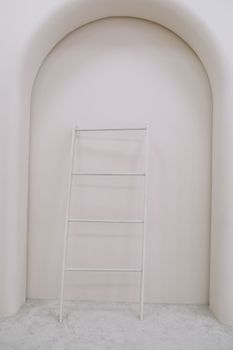 Design interior with stylish wooden ladder, elegant accessories. Stylish home decor. Template. White wall.