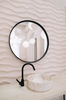 Modern interior with stylish round mirror by beige wall in a cozy room, copy space, elegant accessories in stylish home decor.