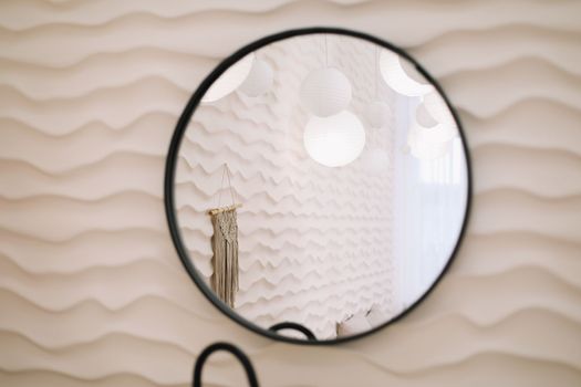 Modern interior with stylish round mirror by beige wall in a cozy room, copy space, elegant accessories in stylish home decor.