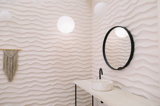 Modern interior with stylish round mirror by beige wall in a cozy room, copy space, elegant accessories in stylish home decor.