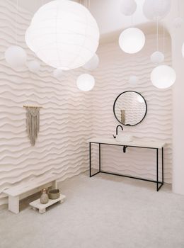 Modern interior with stylish round mirror by beige wall in a cozy room, copy space, elegant accessories in stylish home decor.