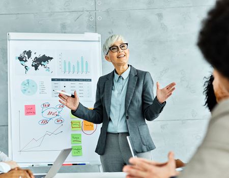 Group of young and senior business people having a meeting or presentation and seminar with whiteboard in the office. Portrait of a senior business woman with gray hair