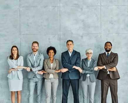 Portrait of a group of young and senior business people holding hands together in the office. Teamwork and success concept