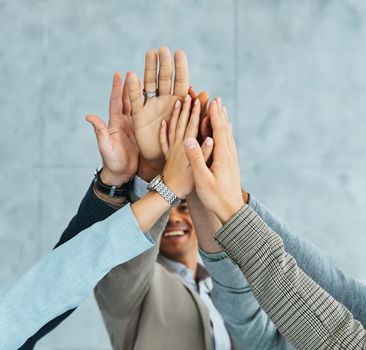 A portrait of young businesspeople celebrating with high five in the office