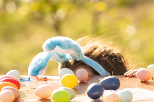 teenage girl paints easter eggs in the garden