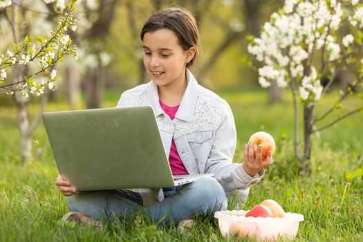 Smart little girl using her laptop in the garden