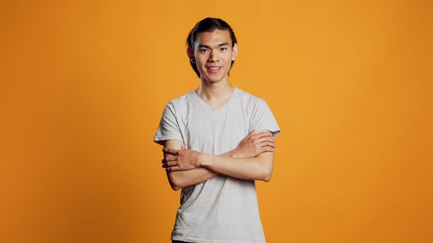Casual asian man posing on studio background, young adult being confident and carefree on camera. Athletic male model acting positive with cool style, hipster having fun for entertainment.