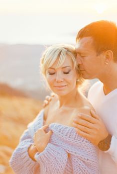 Man hugs a woman from behind and kisses her temple. High quality photo