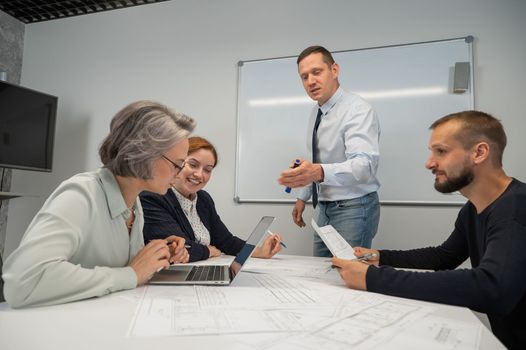 Caucasian man leading a presentation to colleagues at a white board