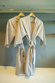Grey colored bathrobe on the hanger in the room at hotel.