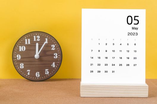 May 2023 Monthly calendar for 2023 year with clock on yellow table.