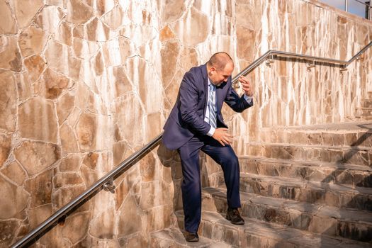 Portrait of a senior professional man in a suit with various problems. A middle-aged businessman with a briefcase descends the stairs.