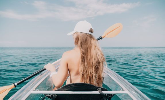 Woman in kayak back view. Happy young woman with long hair floating in transparent kayak on the crystal clear sea. Summer holiday vacation and cheerful female people having fun on the boat.