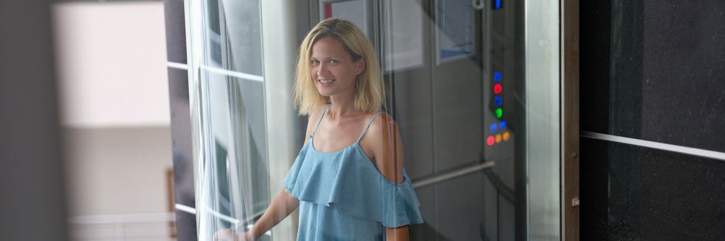 Beautiful smiling woman in transparent glass elevator. Stylish modern elevators in hotels and business centers concept