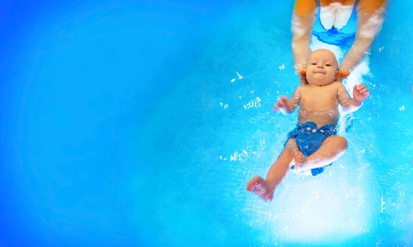 Adorable baby girl enjoying swimming in a pool with her mother early development class for infants teaching children to swim and dive. Swimming instructor doing exercises with a small child in the pool . banner with copy space