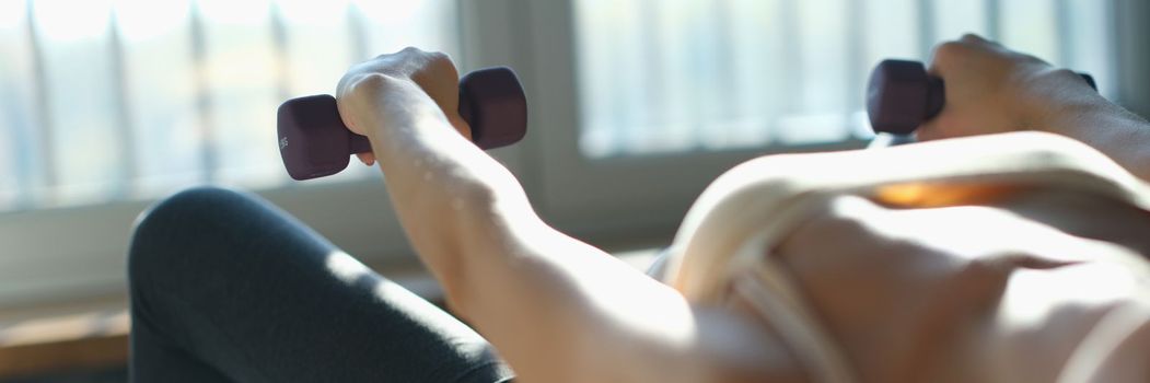 Woman lies on back and trains with ball and dumbbells. home fitness and exercises for spine concept