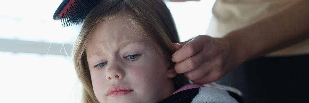 Mother trouble combing unfortunate daughter long hair. Daughter does not allow herself to be combed concept