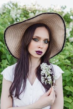 A fashionable girl with dark hair, a spring portrait in lilac tones in summer. Bright professional makeup