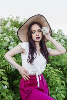 A fashionable girl with dark hair, a spring portrait in lilac tones in summer. Bright professional makeup