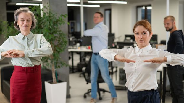 Four office workers warm up during a break. Employees do fitness exercises at the workplace