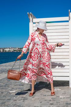 woman in a hat and dress enjoys the blue sea and summer. Welcome summer