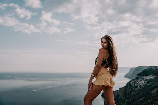 Woman travel sea. Happy tourist taking picture outdoors for memories. Woman traveler looks at the edge of the cliff on the sea bay of mountains, sharing travel adventure journey.