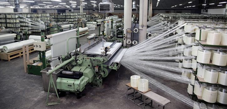 Woven fiberglass roving in a soft cockpit. Fiberglass spools in the workshop.