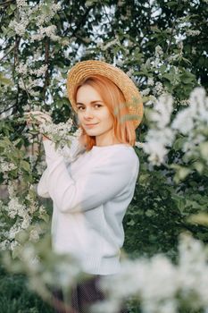 Portrait of a woman in a straw hat in a cherry blossom. Free outdoor recreation, spring blooming garden