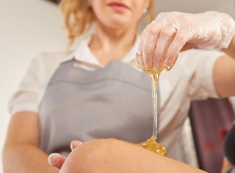 Sugar paste for light depilation. Depilation with sugar paste in the salon on a white background.