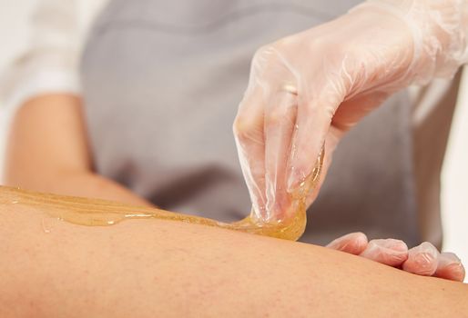 Sugar paste for light depilation. Depilation with sugar paste in the salon on a white background.