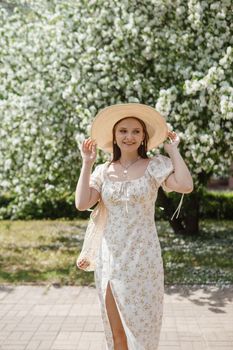 An attractive long-haired woman walks in the spring in the park of blooming apple trees. Spring portrait of a woman