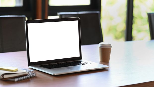 Mock up computer laptop, coffee cup and books on wooden table.