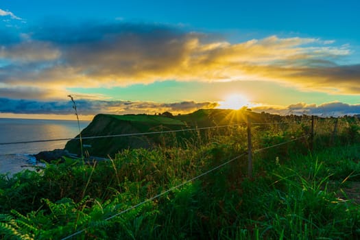 Sunrise sun over the green hills by Atlantic Ocean. Basque country, Spain. Way of St. James, El Camino de Santiago