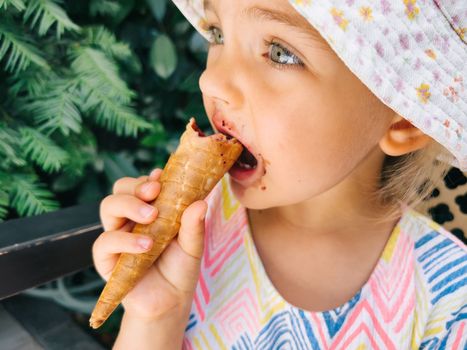 Little girl biting a popsicle in a waffle cone. High quality photo